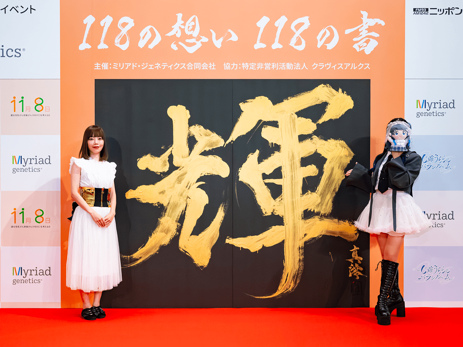 完成した書「輝（かがやく）」の前に立つ真澪さんと七海うららさんの画像